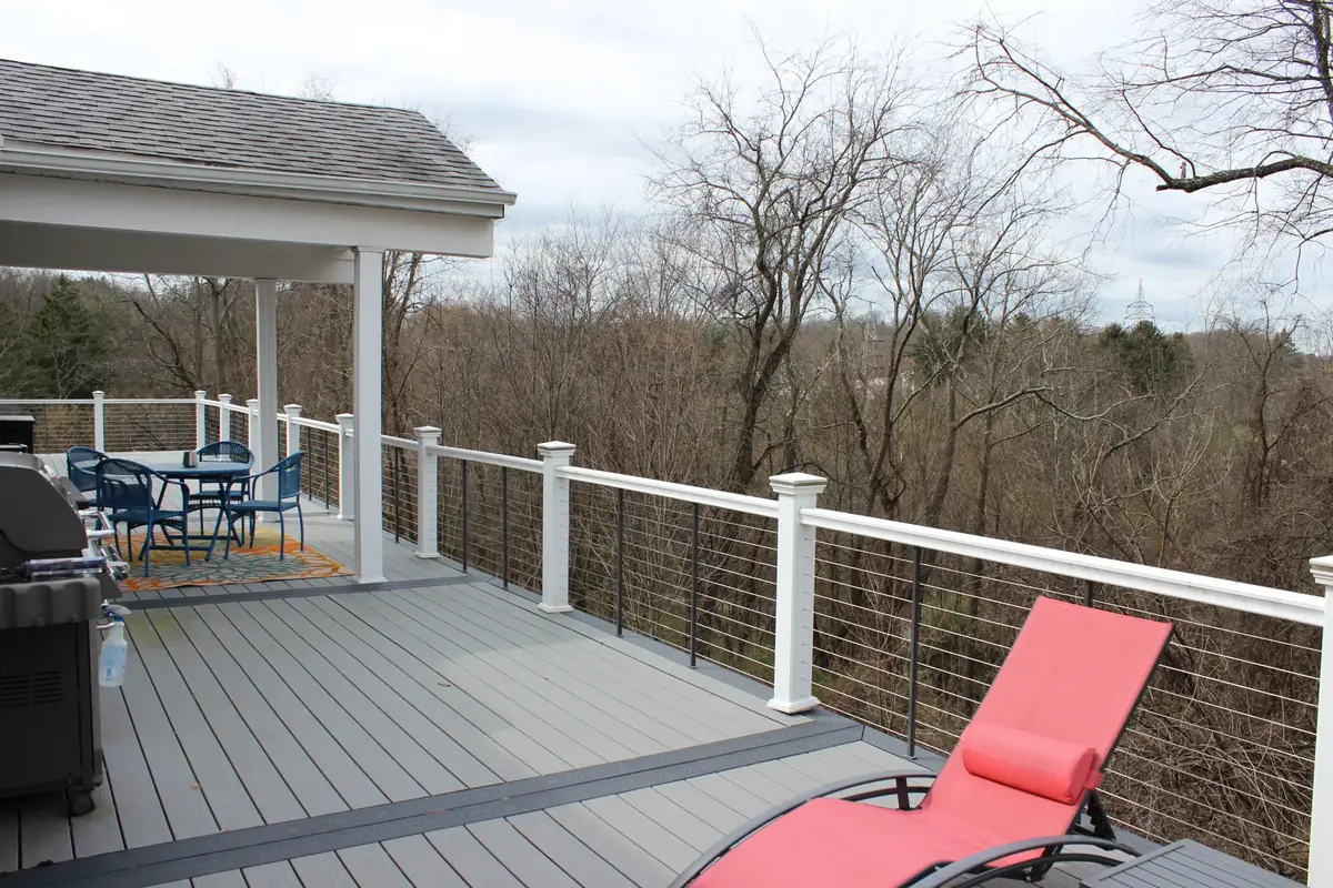 Gray composite deck with white cable railing overlooking the woods